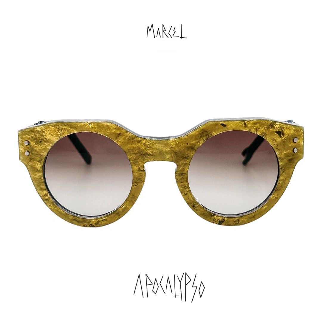 Gold-framed sunglasses with a white background and 'Marcel' branding. Front view.