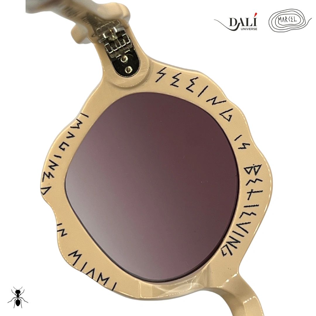 Sunglasses with gold frame and dark lenses, featuring text and brand logos on a white background. Close up of interior engraving.