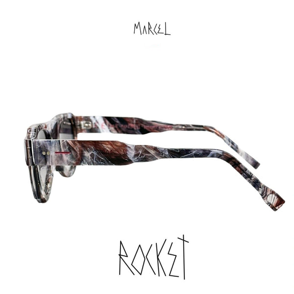 Marbled patterned sunglasses with 'Marcel' branding on a white background. Profile view.