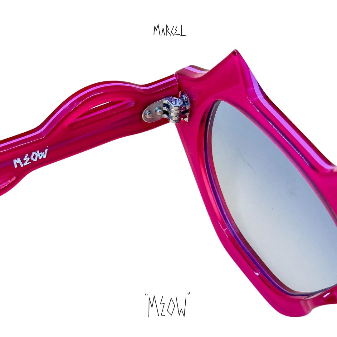 Pink sunglasses with 'MEOW' text on a white background. Close up of temple engravings.