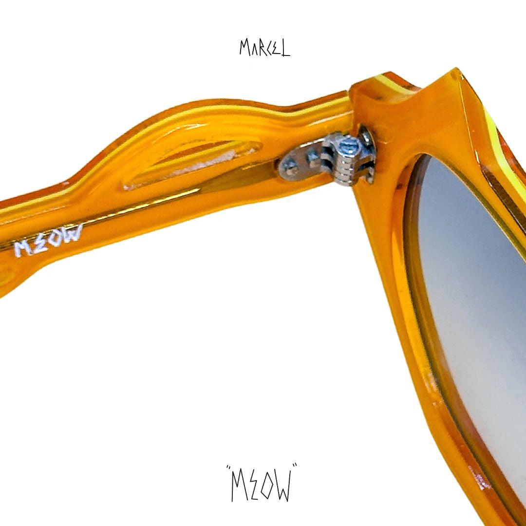 Close-up of a yellow sunglasses frame with 'Meow' branding on a white background. Close up of temple engraving.