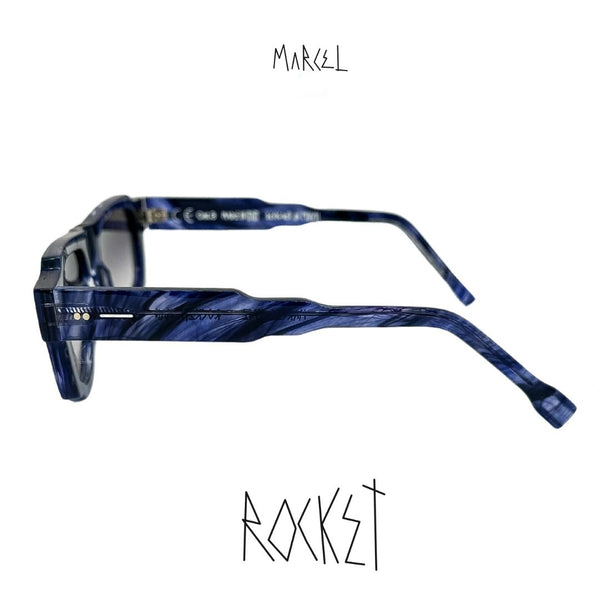 Blue marbled eyeglasses with 'Marcel' branding on a white background. Profile view.