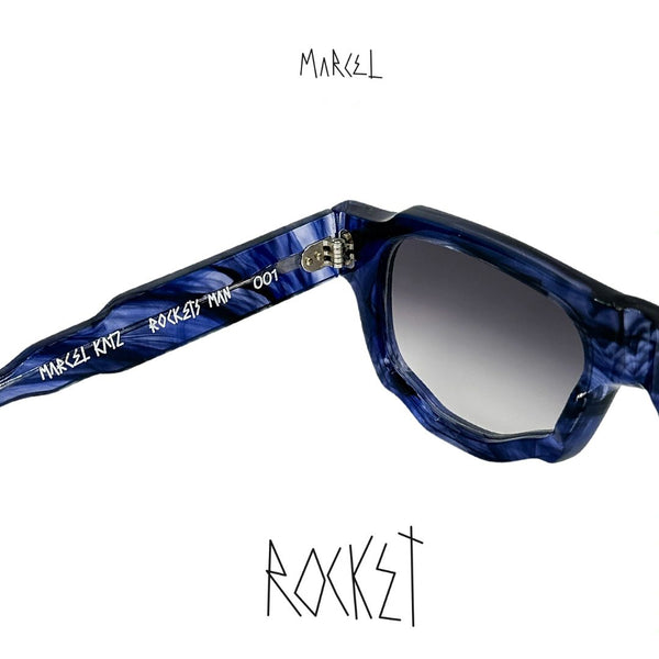 Blue sunglasses with 'Marcel' branding on a white background. Close up of interior engraving.