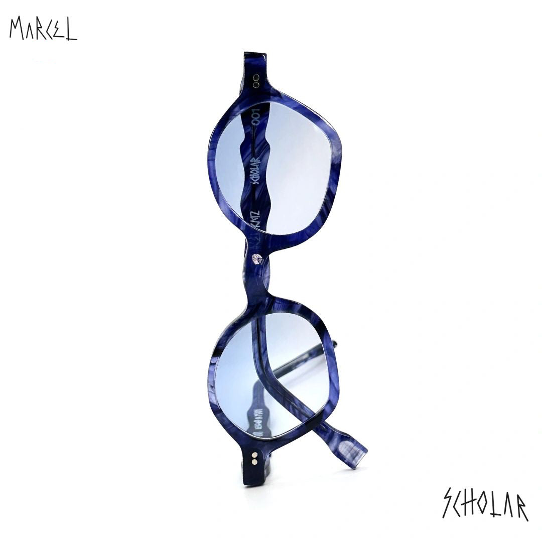 Blue eyeglasses with a white background, featuring the brand 'Marcel' and 'Scholar'. Front view.
