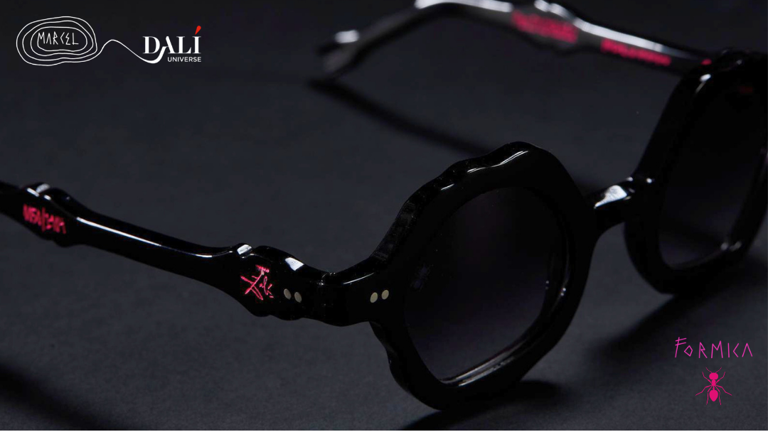 Black round-frame sunglasses with dark lenses and small red logo accents on the temples, shown on a dark background with Dali branding.