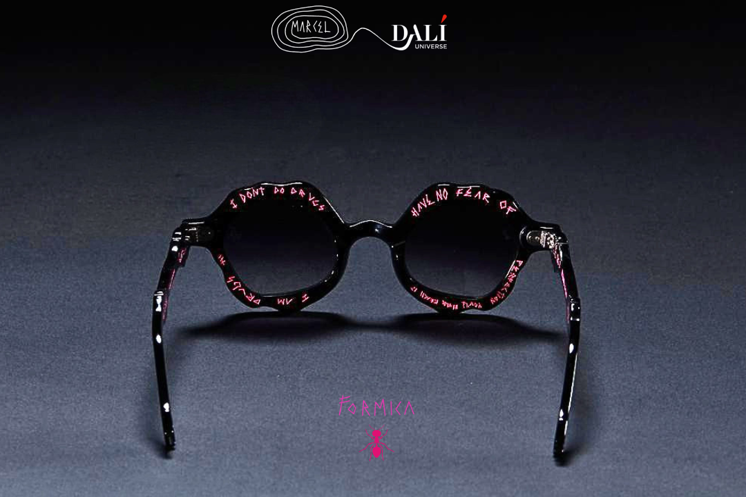 Round sunglasses with dark lenses and patterned frames, shown from the back on a dark gray surface with a black background. The brand name DALI is visible at the top.