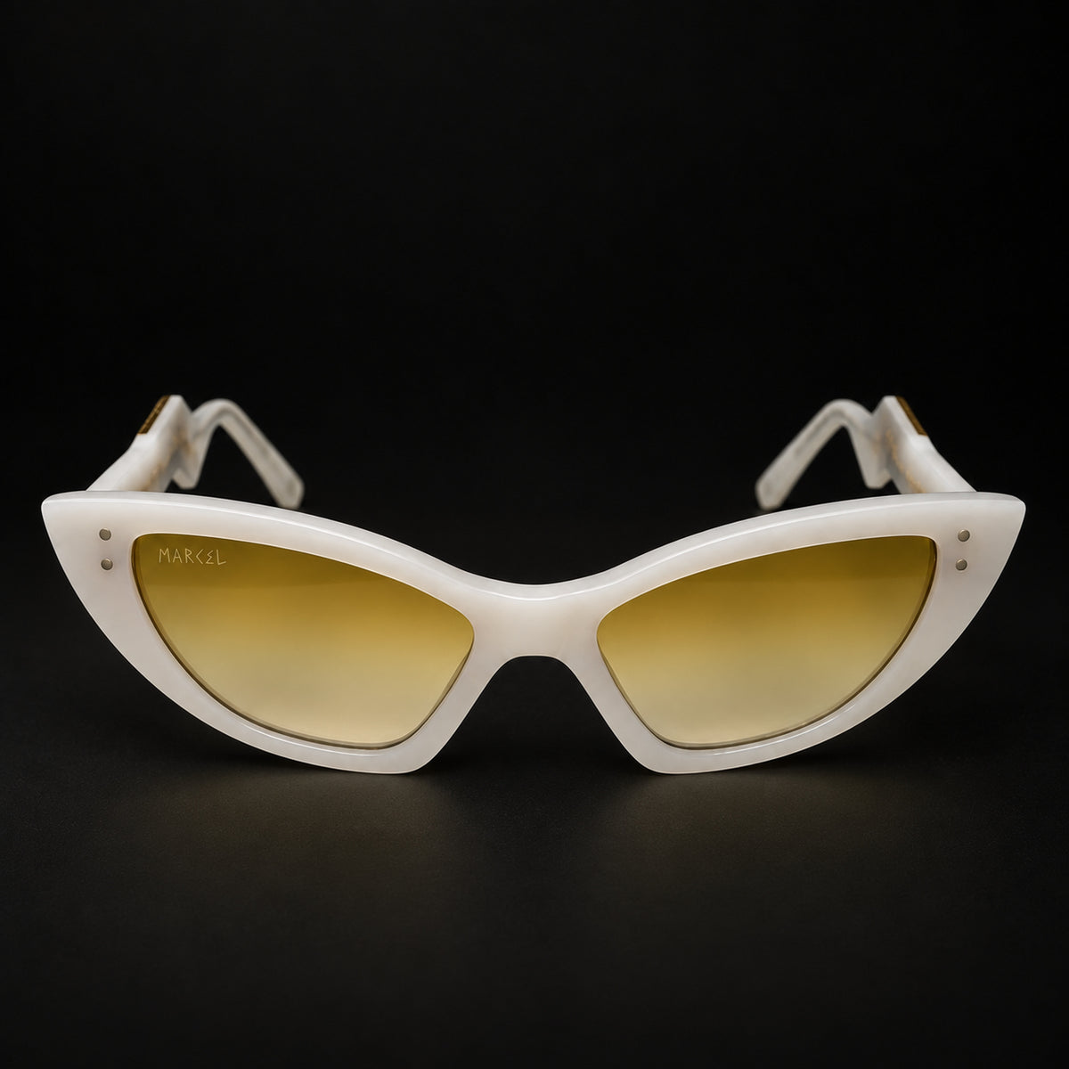 White cat-eye sunglasses with yellow mirrored lenses, shown on a solid black background. The brand name 'MARCEL' is visible on the upper left corner of the lens. Front view.