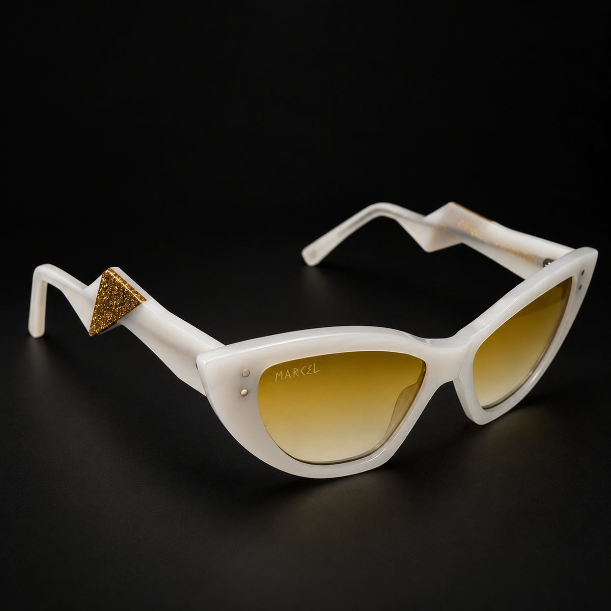 White cat-eye sunglasses with yellow gradient lenses and a gold glitter triangular accent on the temple, shown on a black background. 3/4 view.